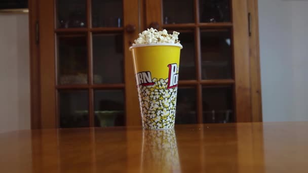 Egy doboz popcorn, amit egy csintalan kéz leüt és gyorsan az asztalra esik..  - Felvétel, videó