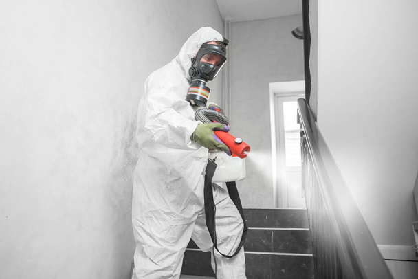 Ontsmetting met het coronavirus. Mensen in hazmats maken schoonmaak in trappenhuis van appartementencomplex - Foto, afbeelding