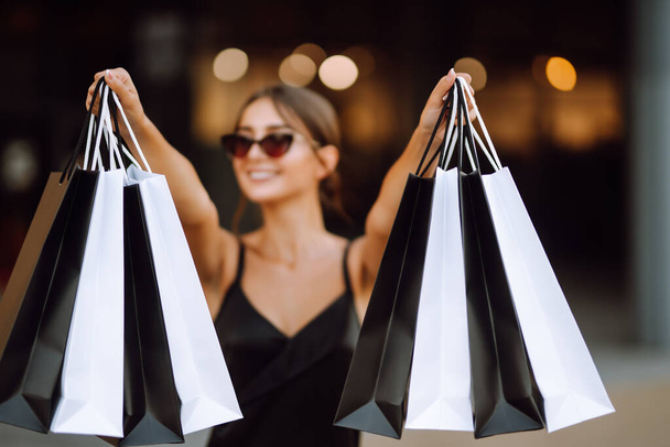 Shopping bags in the hands. Fashion woman with packages after shopping. Black friday, sale, consumerist, lifestyle concept. - Photo, Image
