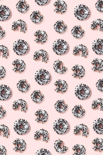 donuts on a pink background top view. Flat lay of delicious nibbled chocolate donuts. used as donut banner or poster background, not pattern - Photo, Image