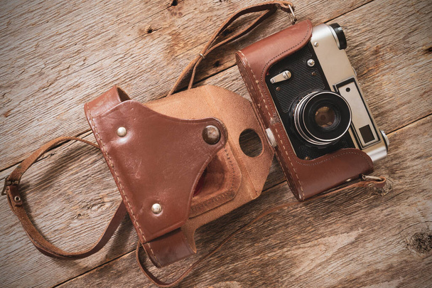 Old film camera lying on the wooden background. Top view. - Photo, Image