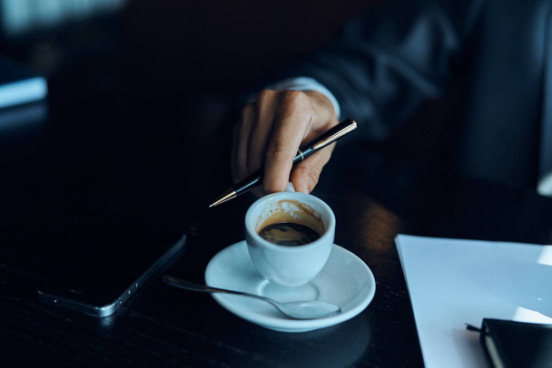 Liikemies kahvilassa dokumentoi kupin kahvia pöydällä viralliset työt - Valokuva, kuva