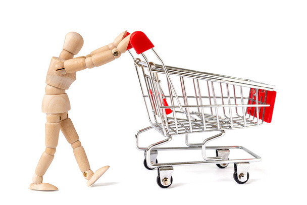 Wooden man pushing a shopping cart. Go shopping looking for deals - Фото, изображение