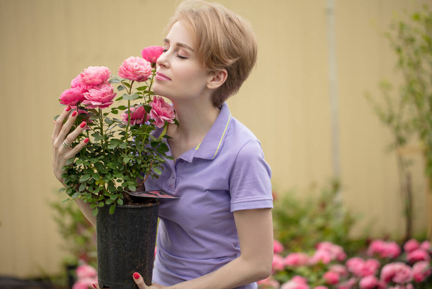 Beautiful young woman with roses posing in garden - 写真・画像