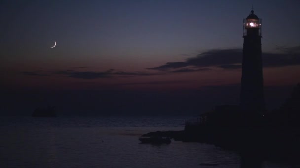 Luna joven después de la puesta del sol en el océano cerca del viejo faro y barco hundido - Imágenes, Vídeo
