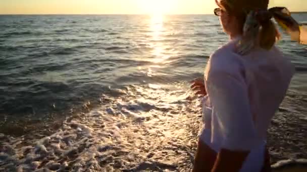 Mujer joven viene al agua en la puesta de sol en la playa de arena, vacaciones en la isla - Metraje, vídeo