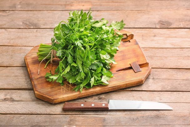 Board with fresh parsley and knife on wooden background - Фото, изображение