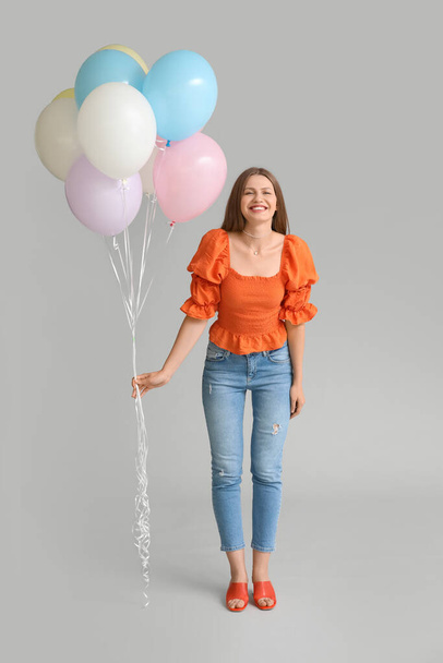 Mladá žena s balónky na šedém pozadí - Fotografie, Obrázek