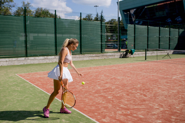 Vrouw die de bal serveert voor een partijtje tennis op het veld - Foto, afbeelding