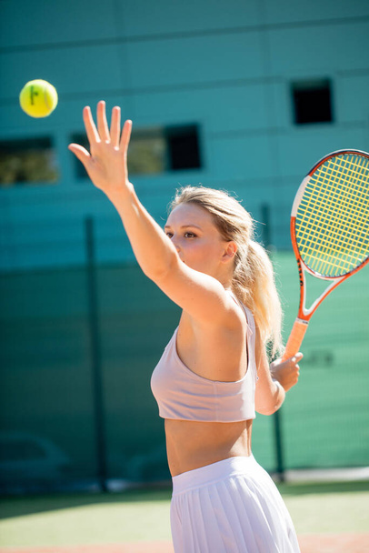 Woman serving the ball for a game of tennis on court - Фото, изображение