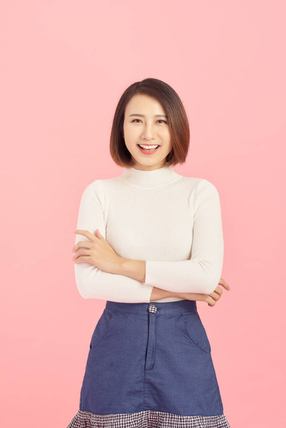 Sorridente di donna asiatica incrociando le braccia e in piedi isolato su sfondo rosa. - Foto, immagini