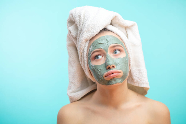 Unhappy teenager female with black clay face mask makes acne therapy in spa - Foto, Imagem