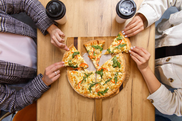 Close-up image of friends sharing traditional Italian pizza and drinking tea in a cafe - Fotografie, Obrázek