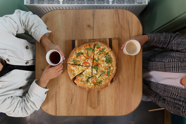 Close-up image of friends sharing traditional Italian pizza and drinking tea in a cafe - Fotoğraf, Görsel