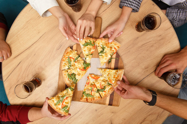 Close-up image of friends sharing traditional Italian pizza and drinking tea in a cafe - Foto, afbeelding