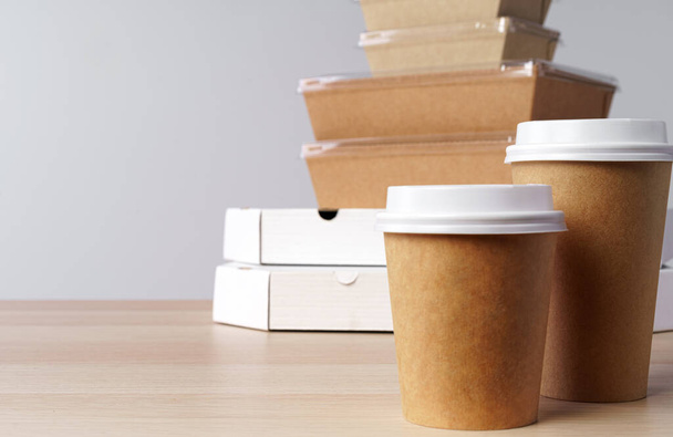 Много различных вынос продовольственных контейнеров, коробка для пиццы, кофейные чашки и бумажные пакеты на светло-сером фоне - Фото, изображение