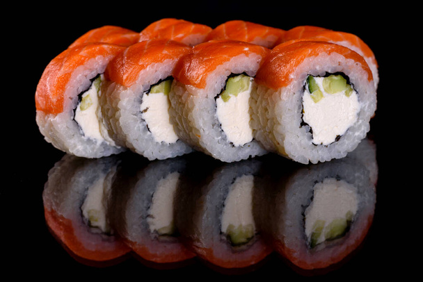 Frische, köstliche Sushi-Rollen auf dunklem Hintergrund. Elemente der japanischen Küche - Foto, Bild