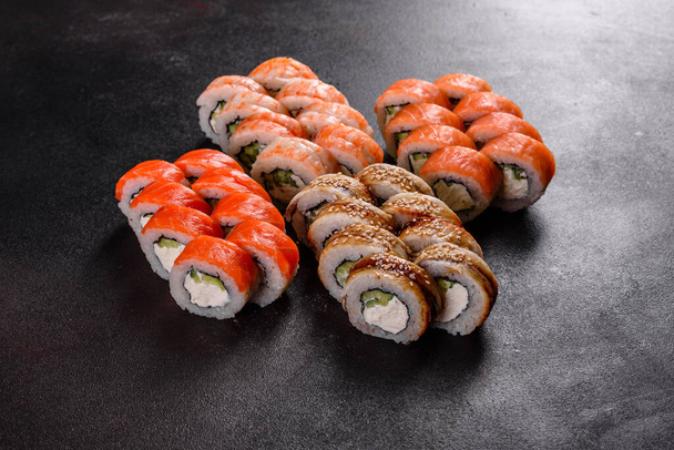 Świeże pyszne sushi bułki na ciemnym tle. Elementy kuchni japońskiej - Zdjęcie, obraz