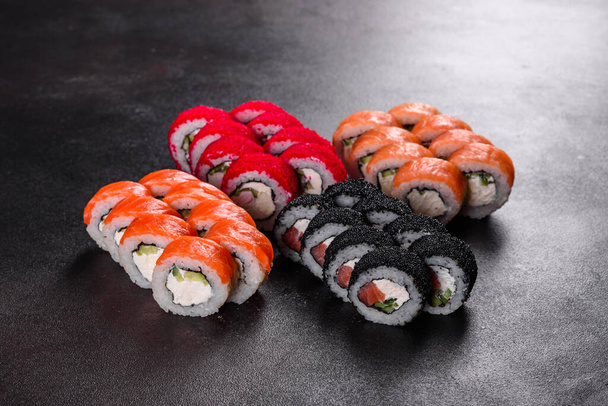 Frescos y deliciosos rollos de sushi sobre un fondo oscuro. Elementos de la cocina japonesa - Foto, Imagen