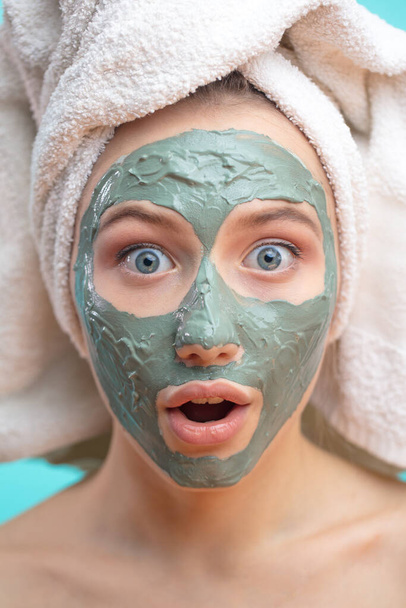 Macro shot of shoked surprised woman with clay facing mask and towel on face - Fotoğraf, Görsel