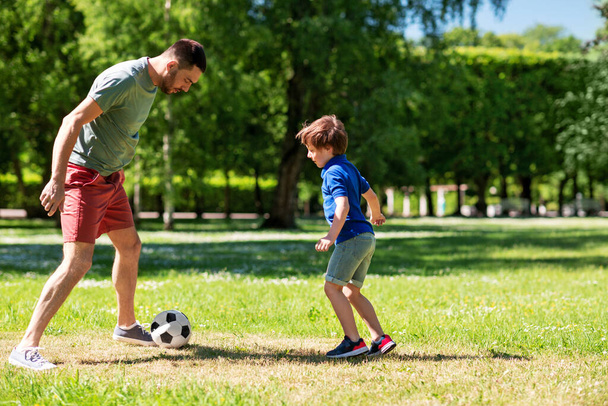 father with little son playing soccer at park - Фото, изображение