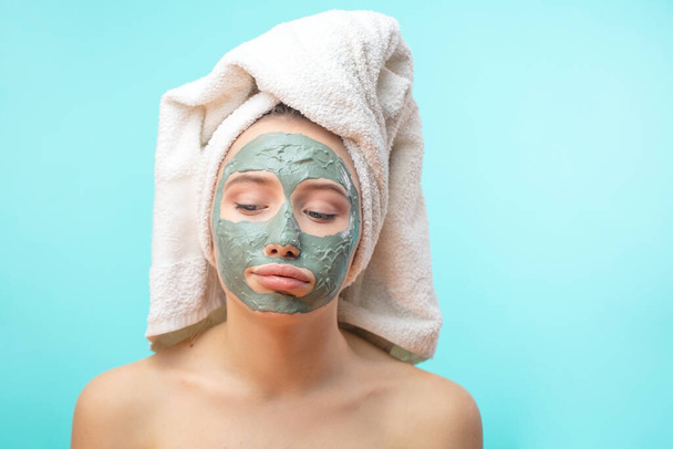 Unhappy teenager female with black clay face mask makes acne therapy in spa - Foto, afbeelding