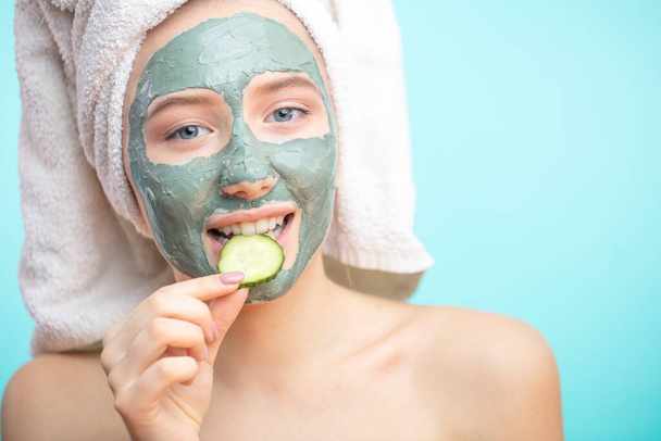Skin care. Cheerful female with clay mask on face and cucumber slices - Foto, imagen
