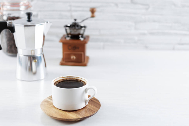 Eine Tasse Kaffee sowie Zutaten und Zubehör zur Kaffeezubereitung auf dem Küchentisch. Kaffee am Morgen. - Foto, Bild