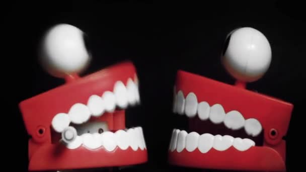 Два игрушечных зуба на черном фоне - Кадры, видео