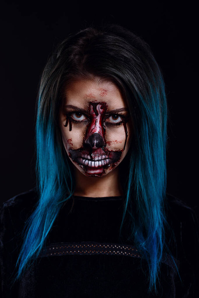 Portret krwawiącej strasznej zombie kobiety w świątecznym makijażu na Halloween. makijaż jest wykonany w formie skóry stawowej w kształcie odwróconego krzyża. Plakat Halloween. - Zdjęcie, obraz