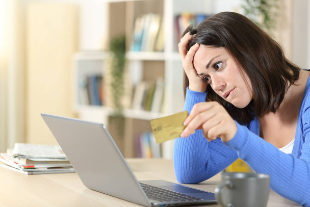 Беспокойная женщина жалуется на покупку онлайн с кредитной картой и ноутбуком на столе дома - Фото, изображение