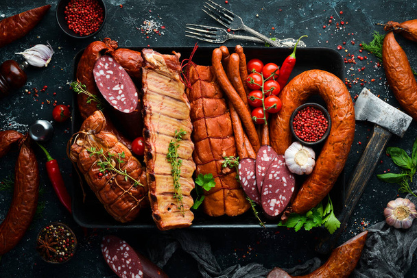 Different sausages and smoked meats on an old wooden table. Top view. Free space for text. - Foto, afbeelding