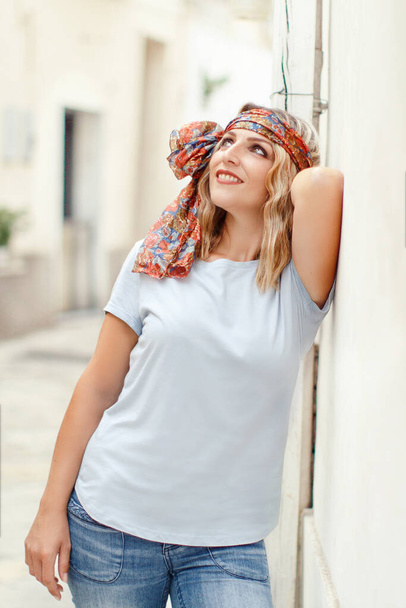 Young women wearing t-shirt and jeans stays near a wall - Foto, imagen