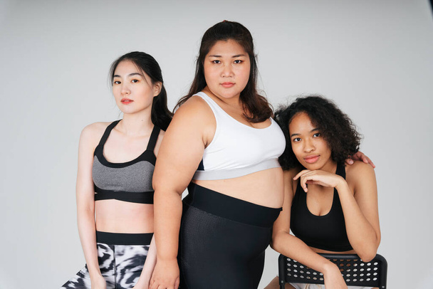 Ryhmä kolme monipuolista naista, joilla on aasialainen ja afrikkalainen urheilu rintaliivit asu valkoisella taustalla. - Valokuva, kuva