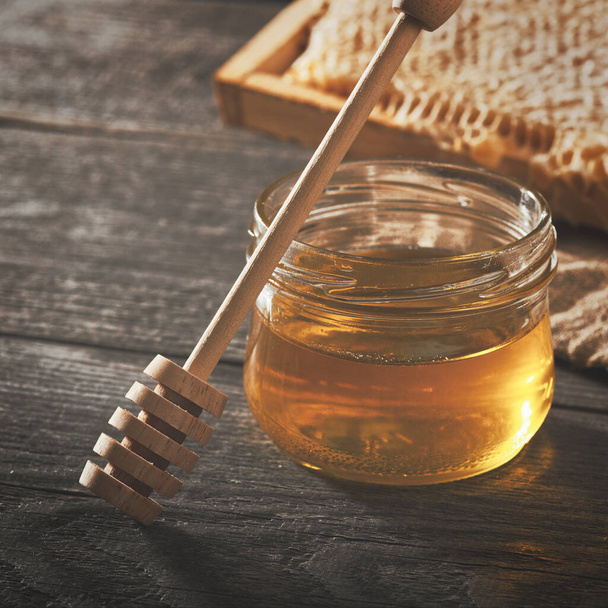 Sfondo miele. Miele con tuffatore di miele in legno sul tavolo di legno - Foto, immagini