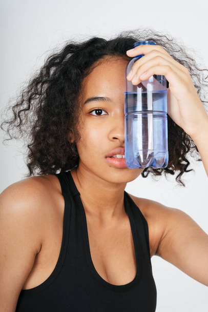 Portrait d'une femme africaine et thaïlandaise métissée tenant une bouteille d'eau. - Photo, image