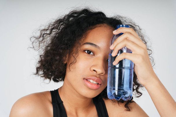 Portrait of mixed race african and thai woman holding a bottle of water. - Photo, image