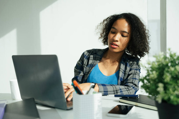 Afrikkalainen liiketoiminnan nainen työskentelee toimistossa kannettavan tietokoneen ja älypuhelimen kanssa. - Valokuva, kuva