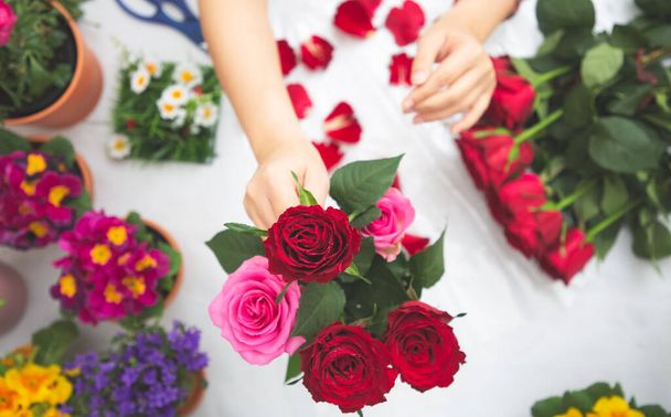 Mujer Preparándose para recortar rosas rojas y rosas y hermosos arreglos florales en el hogar, arreglos florales con florero para regalar para el día de San Valentín y negocios en la familia en la mesa - Foto, imagen