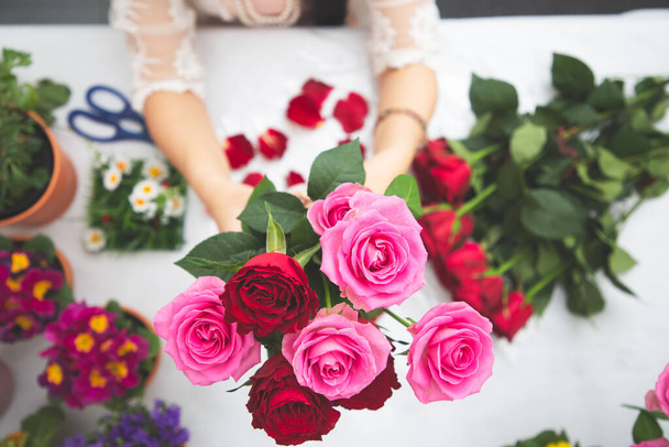 Mulher Preparando-se para aparar rosas vermelhas e rosa e belos arranjos de flores em casa, arranjos de flores com vaso para presentear para o Dia dos Namorados e negócios na família na mesa - Foto, Imagem