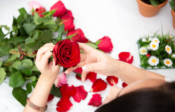 Mujer Preparándose para recortar rosas rojas y rosas y hermosos arreglos florales en el hogar, arreglos florales con florero para regalar para el día de San Valentín y negocios en la familia en la mesa - Foto, Imagen