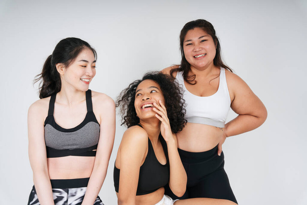 Groep van drie diverse vrouwen met aziatische en Afrikaanse in sport beha outfit op witte achtergrond. - Foto, afbeelding