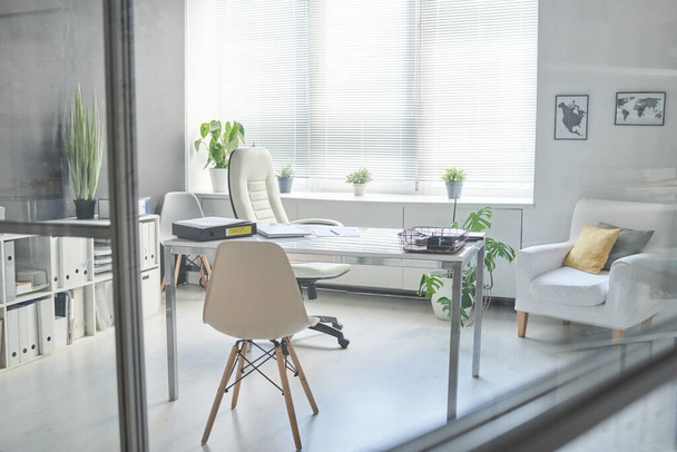 Pas de personnes à travers un plan en verre de l'intérieur minimaliste du lieu de travail dans la salle de bureau moderne en couleur blanche - Photo, image