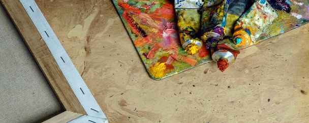 Фото трубки з різнокольорової олійної фарби та пензлі художника на полотні крупним планом
. - Фото, зображення
