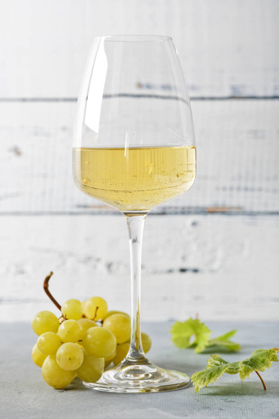 Glass of white wine on vintage wooden table. Light background - Fotó, kép
