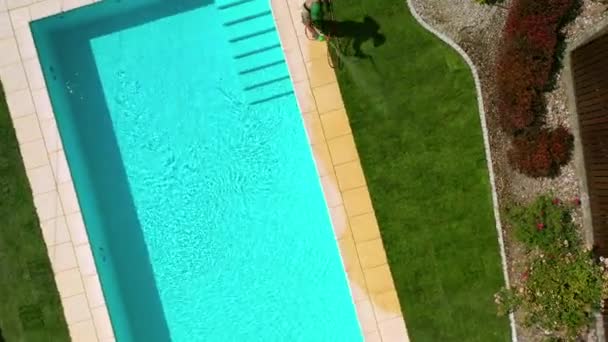 Luftbild eines männlichen Landschaftsgärtners, der im abgeschiedenen Hinterhof eines Hauses einen schmalen Streifen frisch gerollten Erdbodens bewässert.  - Filmmaterial, Video