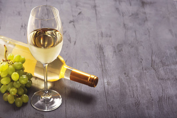 Стакан белого вина и винограда на винтажном деревянном столе. - Фото, изображение