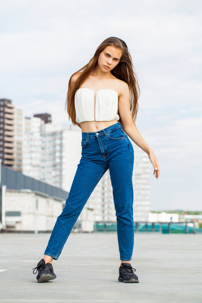 Full body portrait of a young beautiful brunette woman in blue jeans - Фото, зображення