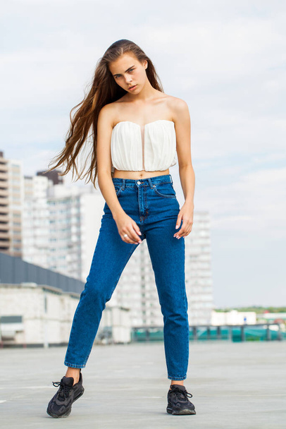 Full body portrait of a young beautiful brunette woman in blue jeans - Фото, изображение