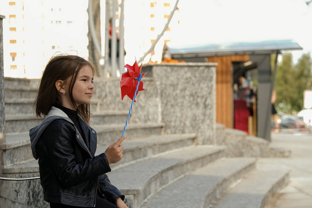 Pieni tyttö kaupunkiympäristössä punaisella tuulenpuuskalla - Valokuva, kuva